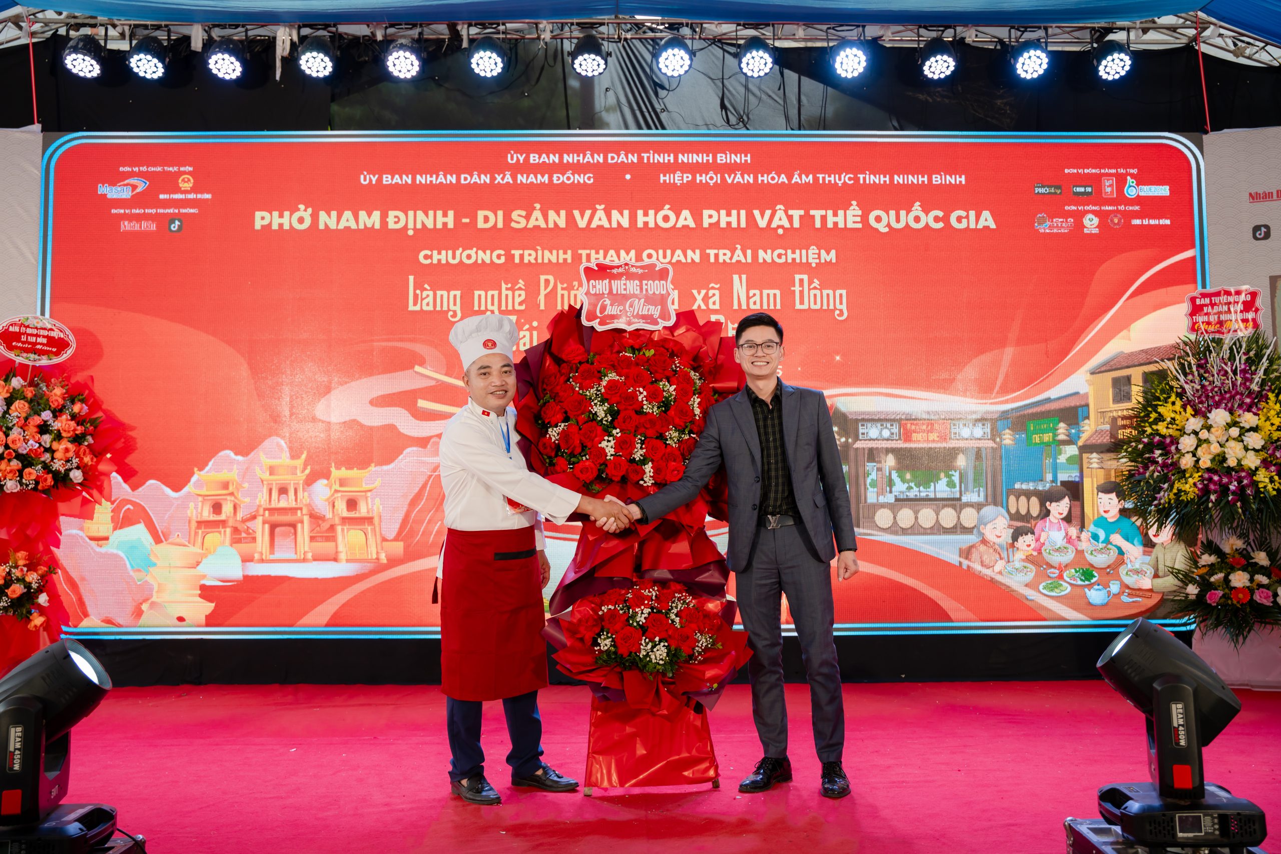 Tổng giám đốc Chợ Viềng Food Vũ Văn Khoa tặng hoa chúc mừng Nghệ nhân Văn hoá Ẩm thực Việt Nam: Cồ Như Đồi, Phó chủ tịch Hiệp hội Văn hoá Ẩm thực Tỉnh Ninh Bình - Chi hội trưởng Phở Vân Cù